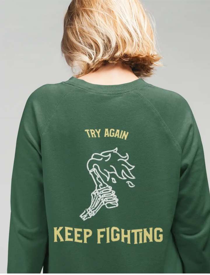a female model wearing olive green sapienwear women's sweatshirt with the keep fighting graphic on the back side.