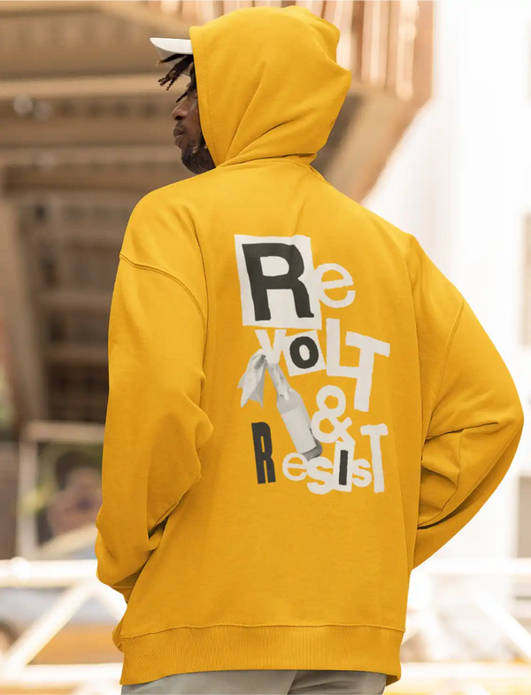 a model wearing a golden yellow Sapienwear men's hoodie with the revolt and resist design on the back side